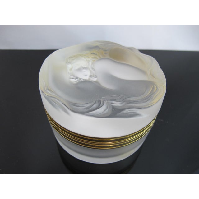 Lalique Daphne round glass box with hinged lid showing a seated nymph with long locks of hair raveling around the outer...