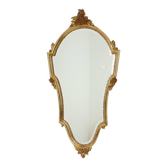 A fantastic gold-colored deknudt mirror with a decorative crest and beveled glass, executed in the classic louis xvi...