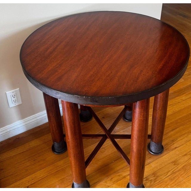 A Mid Century Modern table with the unusual design of having six legs. It is made from mahogany with dark iron shoes and a...