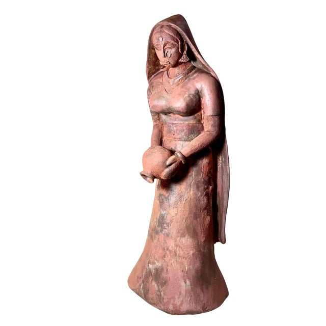 A charming pair of late 19th century terracotta figures depicting an Indian man and woman engaged in a quiet domestic...