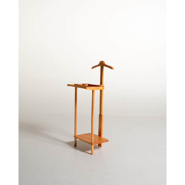Beech frame with a shaped coat hanger, a storage tray with two circular slots, a trouser bar, and a lower shelf....
