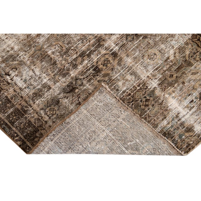 Beautiful vintage distressed hand-knotted wool rug. This rug has a brown field, with some subtle ivory accents, and is...