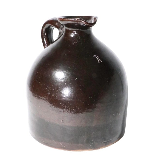 Antique stoneware whiskey jug in classic Albany slipware glaze, having a sculptural pouring spout, with applied handle and...