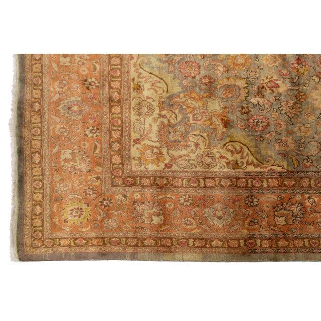 This Persian hand-knotting wool and silk rug features a gray field with a peach-designed frame and multicolored accents....