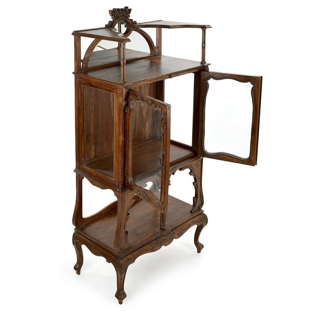 This glazed cabinet in carved solid wood, topped with an elegant arched mirror, perfectly illustrates the charm of antique...