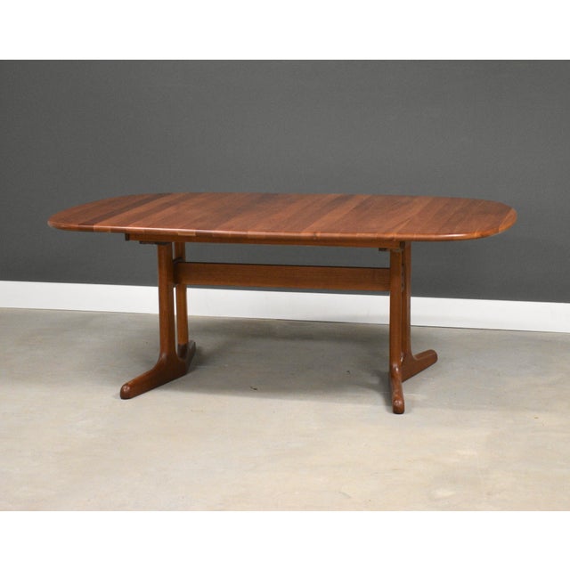 A mid century modern rounded rectangular solid cherry dining table with a pedestal base and two 19.375” leaves which fully...