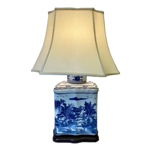Blue and White Porcelain Tea Jar Table Lamp Decorated With an Asian Landscape Scene Resting on a Wooden Base With Cream Colored Lampshade