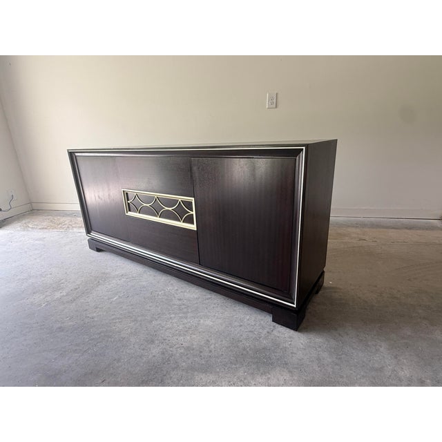 Elegant Ethan Allen Eastview sideboard featuring a rich, dark wood finish accented by distinctive brass-tone geometric...