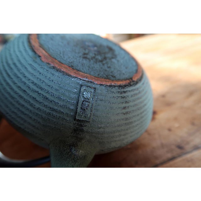A vintage cast iron teapot in the traditional Japanese tetsubin style, distinguished by its elegant ribbed surface and...
