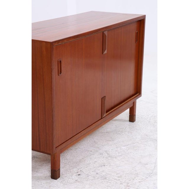 Vintage mahogany chest of drawers with two large sliding doors and a clean, linear design. The doors overlap, revealing a...