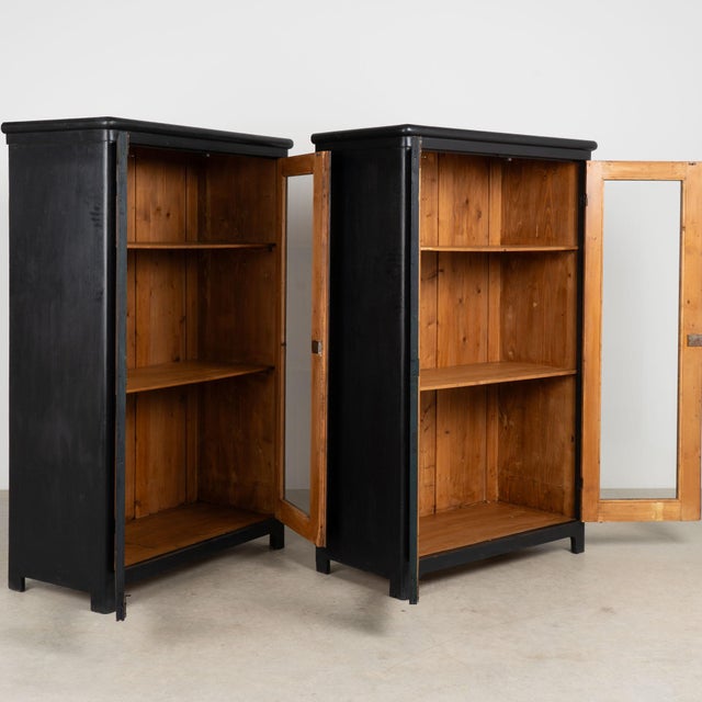 Pair of 20th century bookcases, crafted in pine and given a newer black painted finish. Long glass panels provide generous...