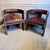 A striking pair of African hardwood and leather armchairs, richly decorated with carved detail, inlay and brass studwork....