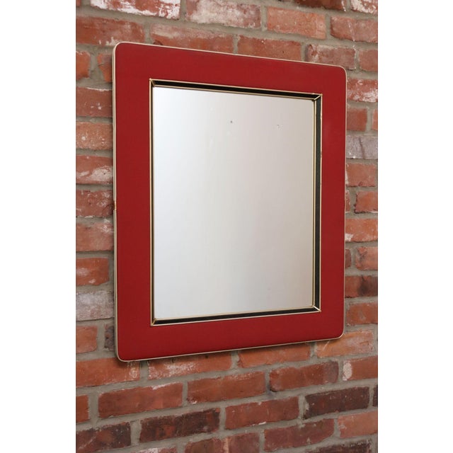 Vintage wall mirror designed by Umberto Mascagni (ca. 1950s, Italy). Composed of a wooden frame wrapped in a raspberry red...