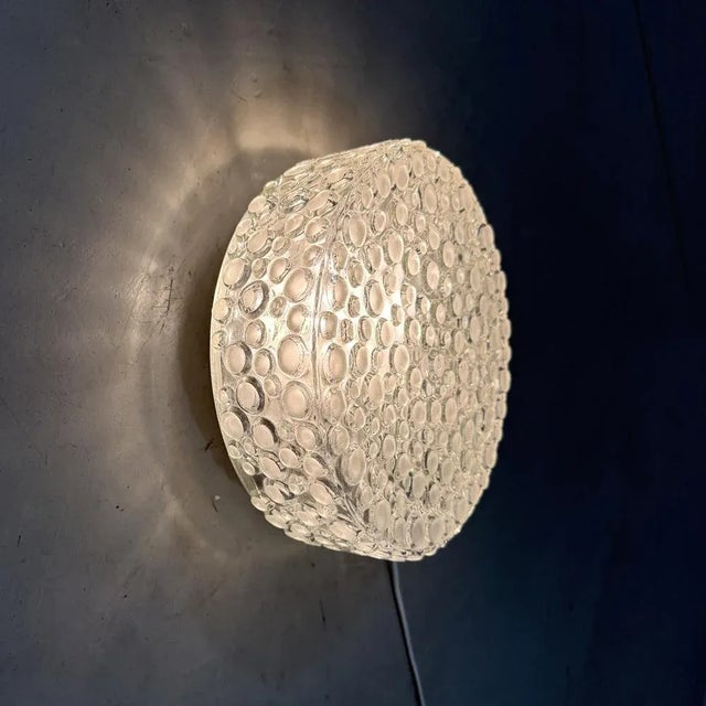 Round glass wall / ceiling lamp. Thick clear glass with matted glass bubbles. Black steel wall/ceiling fastening, 1 large...