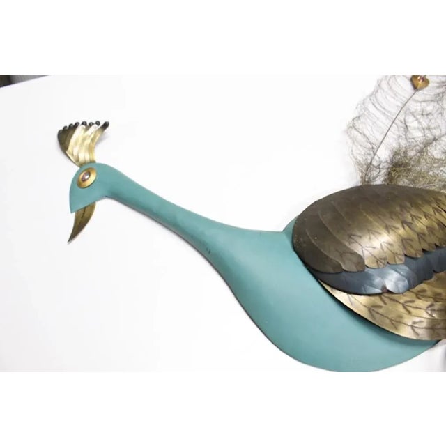 Unique, large brass peacock has a brass brush tail with colorful glass jewels, painted body, perched on a large wooden...