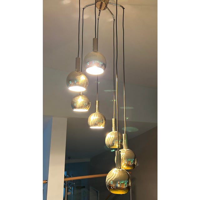 Mid century Space Age pendant light, featuring 7 brass spheres with louvered top, arranged in a circular cascade alike...