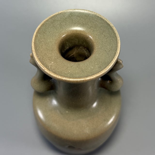 Classic Chinese official‑style celadon vase with decorative phoenix‑form side handles and flared disk mouth. Covered in...