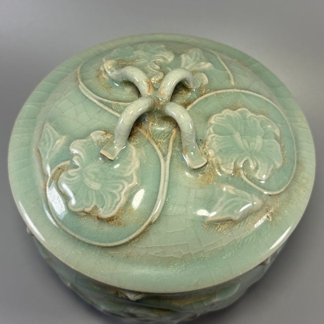 Classic Chinese celadon lidded jar, fitted with matching lid featuring twisted‑loop finial. The body and lid are decorated...
