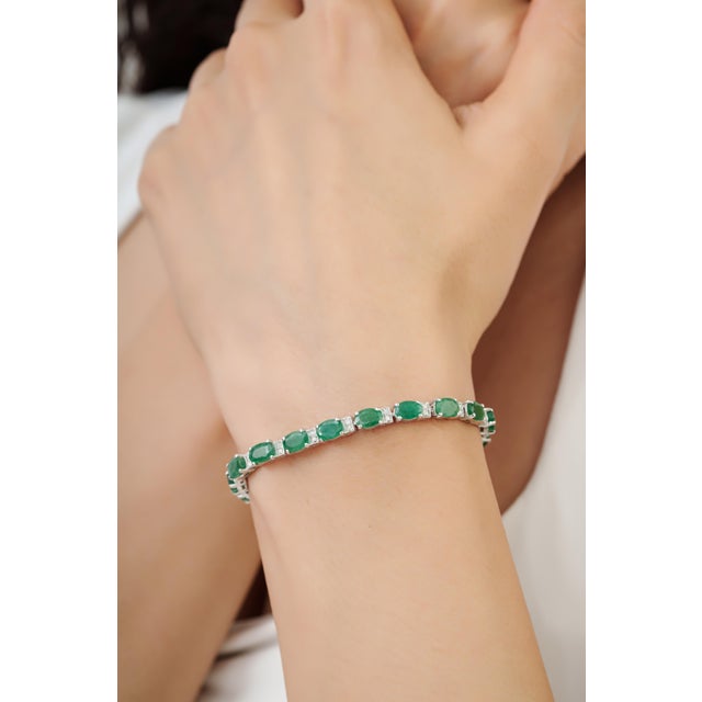 This classic tennis bracelet features 10.05 carats of natural oval-cut emeralds, each measuring approximately 4 x 6 mm,...