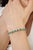 This classic tennis bracelet features 10.05 carats of natural oval-cut emeralds, each measuring approximately 4 x 6 mm,...