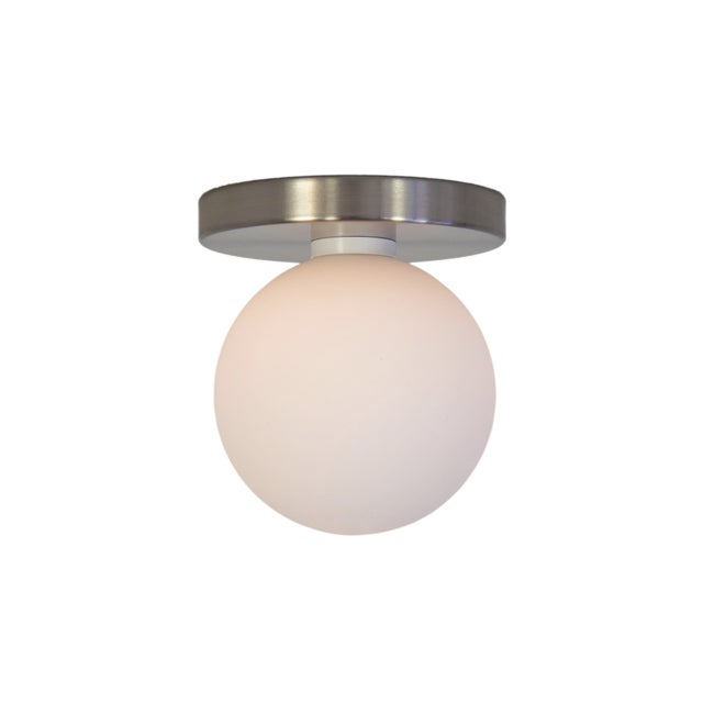 Minimal from top to bottom. This black flush mount pairs a metal base with a soft glass globe. Cool, calm, and quietly...