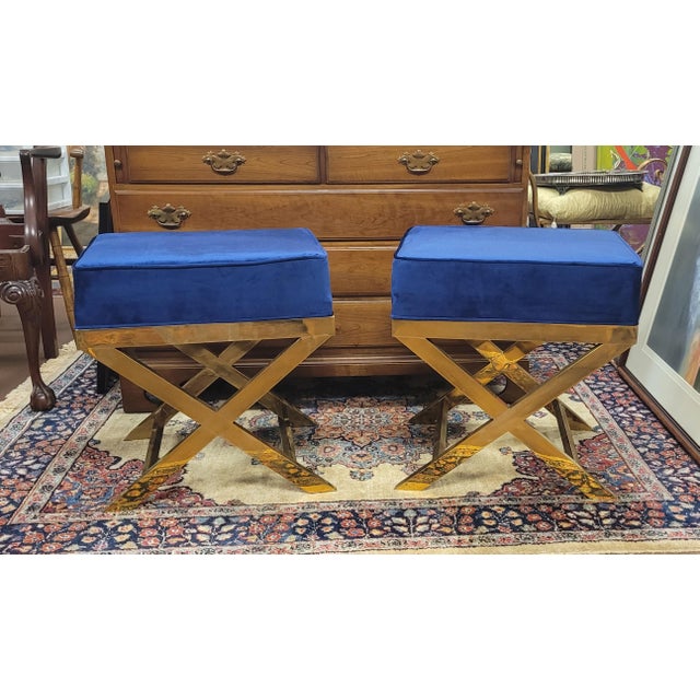 Find pair of X-base stools or bedside benches in lacquered brass and royal blue velveteen upholstery. Each measures 20 in...