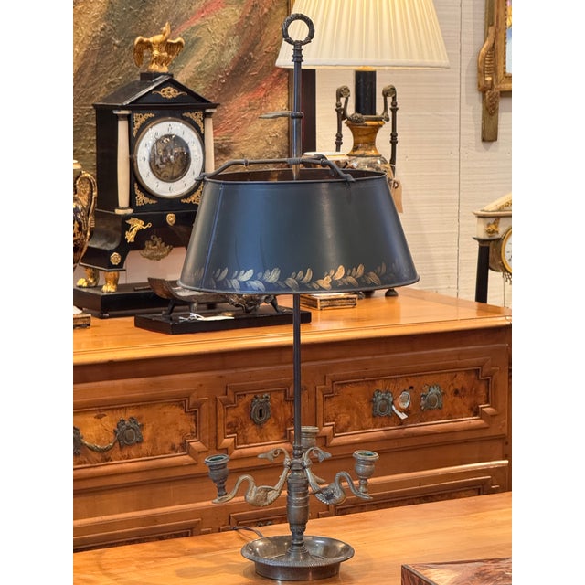 A French bouillotte lamp featuring a dark green tole shade with gilt leaf decoration and adjustable height. The patinated...