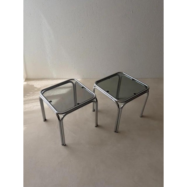 Chrome, smoked glass, and a construction in which virtually no right angles can be found. This set of two side tables was...