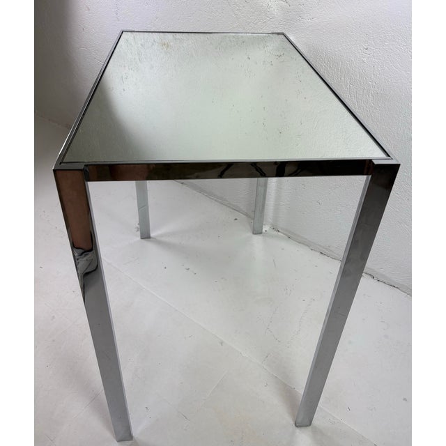 This is a mid-century vintage chrome and mirrored topped side table. This vintage table has a minimal design with a...