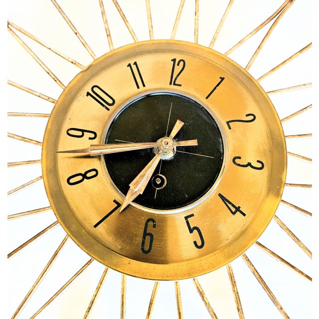 A Vintage MCM Starburst Wall Clock with key. Features brass finish and wood accents, original mechanical wind up action,...