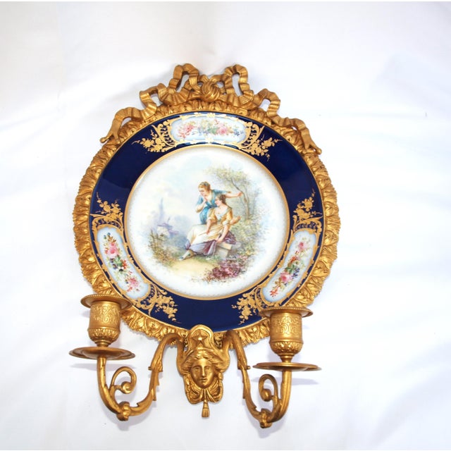 An antique pair of hand painted cabinet plates mounted as wall candle sconces. Plates are hand painted depicting a French...