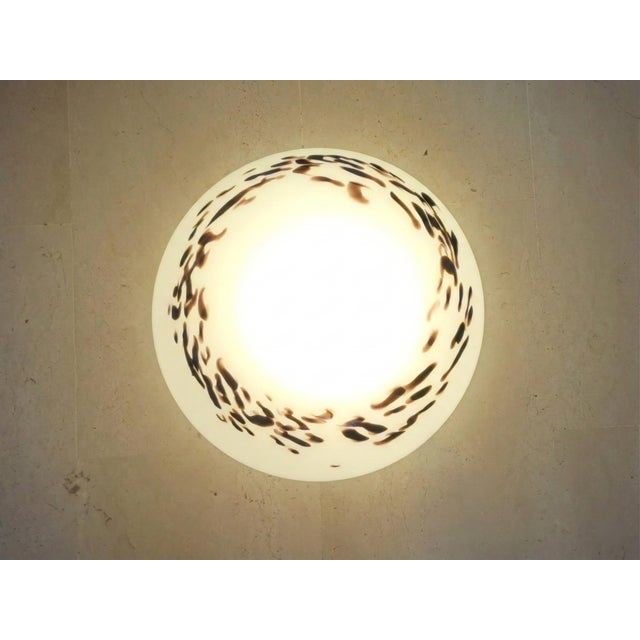 Murano glass ceiling lamp, dating back to the 1990s. The milky glass disc features an irregular spotted pattern...
