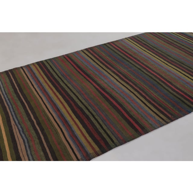 Made with handwoven wool circa 1950-1960, this 6x11 vintage flat-weave Kilim is a particularly atmospheric and sought-...