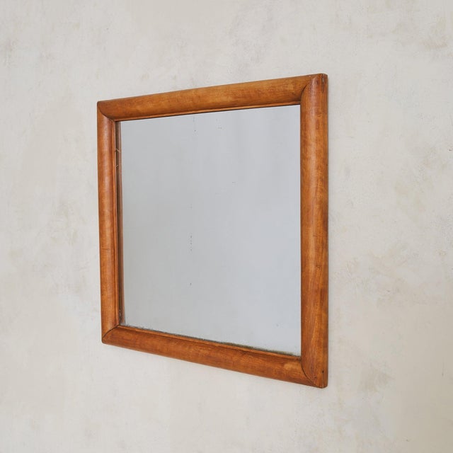A 1950s Italian wall mirror with a soft, architectural presence. Framed in solid wood, its rectangular form features...
