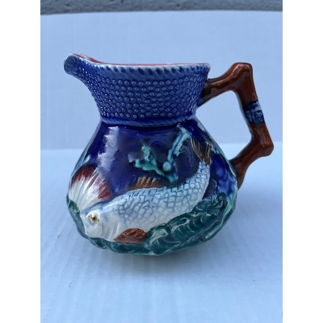 A single vintage majolica pottery pitcher with fish motif and handle.