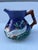 A single vintage majolica pottery pitcher with fish motif and handle.