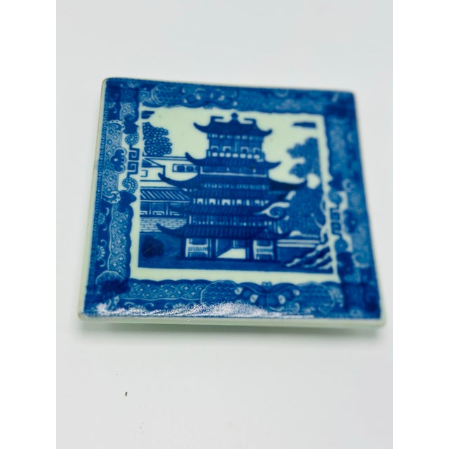 Charming antique English ironstone trivet featuring a classic blue-and-white transferware design depicting a traditional...