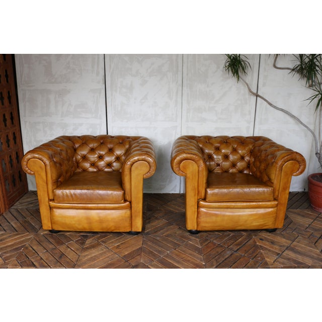 Beautiful vintage pair of English Chesterfield club chairs in rich honey-brown distressed leather. Featuring classic...