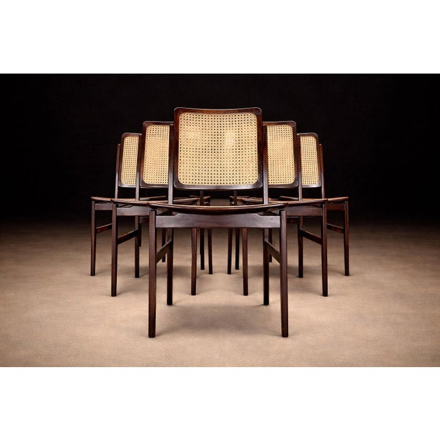 A set of six dining chairs produced in the 1960s, crafted in solid Brazilian rosewood with woven cane seats and backs. The...