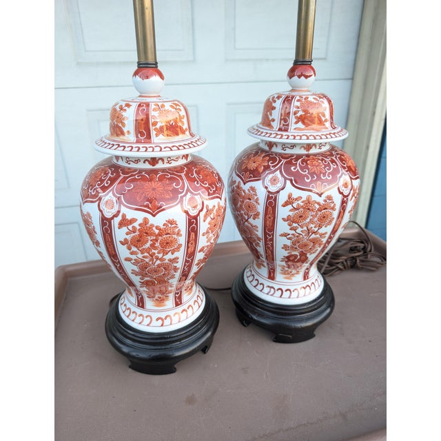 This pair of vintage porcelain ginger jar table lamps feature a classic 1950s design with intricate red-orange floral...