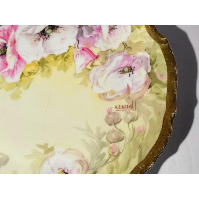 Hand‑painted Limoges porcelain plate signed by A. Lajus, dating from circa 1890–1920. A gentle yellow ground holds soft...