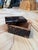 A small rectangular box with a curved, dome-shaped lid, finished in a glossy faux-tortoiseshell pattern in rich tones of...