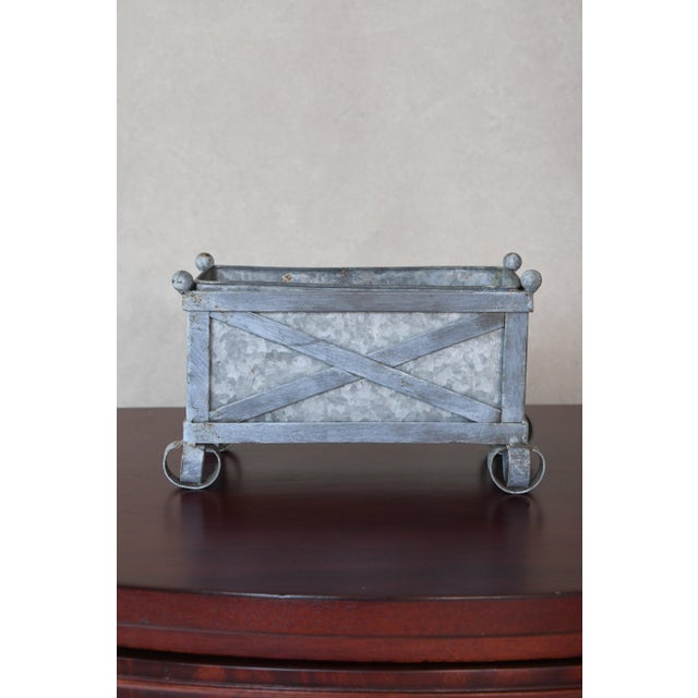 A small rectangular planter with X-cross banding on each long side, four ball finials at the top corners, and scrolled...