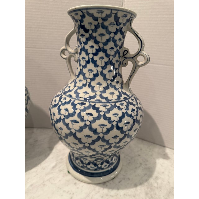 A pair of vintage blue and white ceramic vases having delicate handles and a solid blue band around the bottom. A perfect...