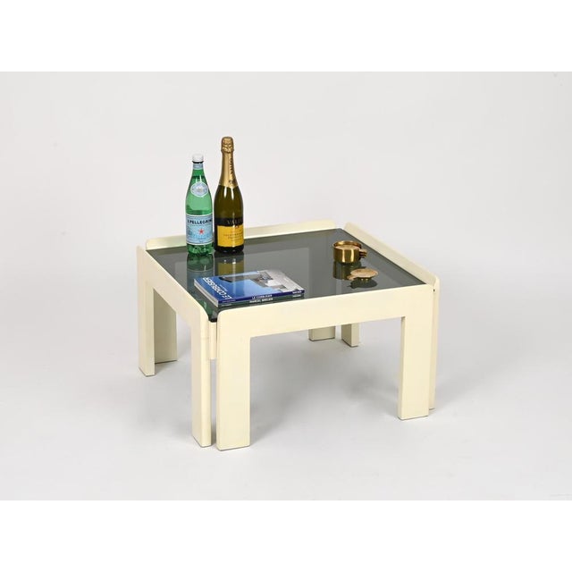 Gorgeous Mid-Century square coffee table in beautiful ivory-white lacquered wood, completed by a smoked glass top. This...