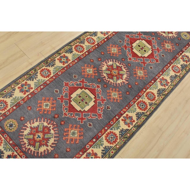 A tribal Caucasian Kazak runner hand-knotted with fine wool on a cotton foundation. This rug features medallions...