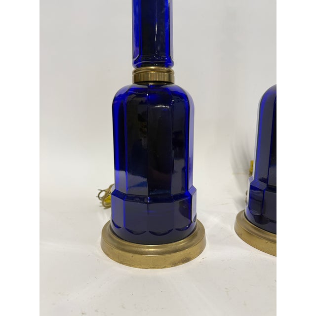 A striking pair of Vaughan table lamps, designed with deep cobalt blue glass bodies and brass mounts in a refined...