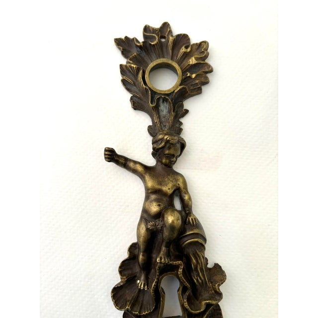 A Bronze keyhole Escutcheon or door plate featuring a small boy or putto pouring water from a jug. This piece measures 9”...
