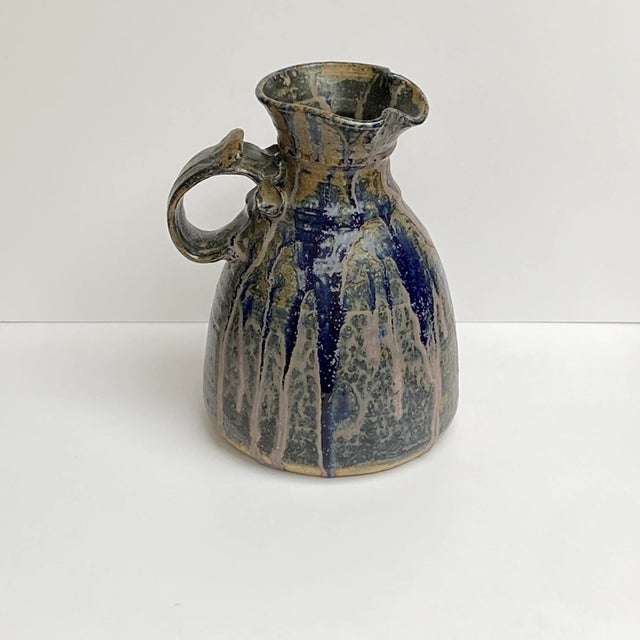 BEAUTIFUL STONEWARE PITCHER hand thrown and glazed with drips and runs of color blue grey, pinkish/mauve. It has a curvy...