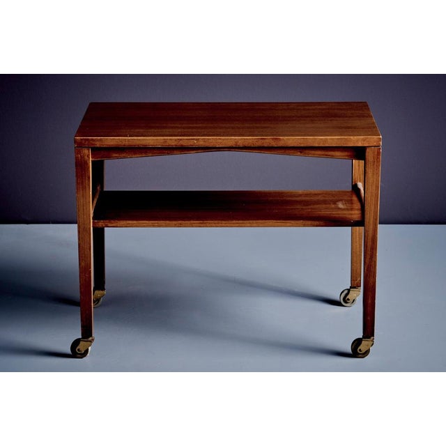 Renz Side Table on castors. Crafted from Walnut, featuring a gently curved lower stretcher and refined, sculptural lines....